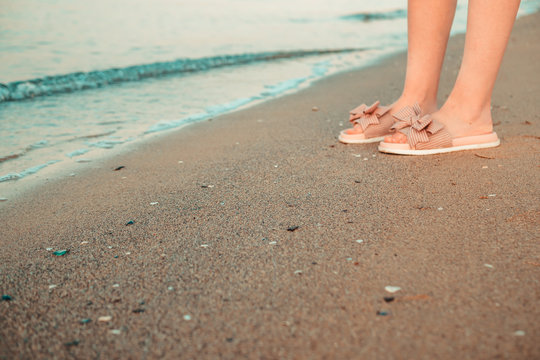 girl stands on the beach in slippers the seashore close-up