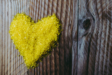 Coeur jaune en sels sur un arrière plan bois
