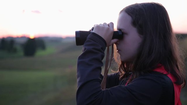 Teenage girl looking through binoculars.