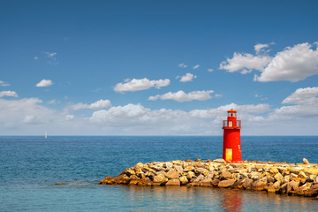 Mediterranean seascape with an old red lighthouse on a rocky breakwater pier in a sunny summer day with blue cloudy sky, Porto Maurizio, Imperia, Liguria, Italy - Powered by Adobe