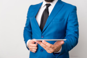 Businessman in blue suite with a tie holds lap top in hands.