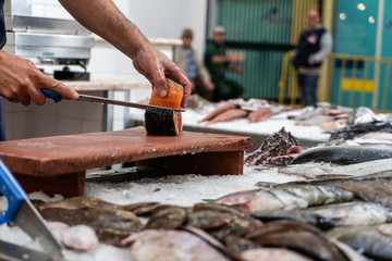 Fish monger cutting salmon at the market