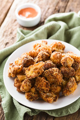 Fried breaded cauliflower florets on plate with fry sauce in the back (Selective Focus, Focus on the cauliflowers in the front)