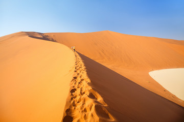 Kids climbing up red sand dune