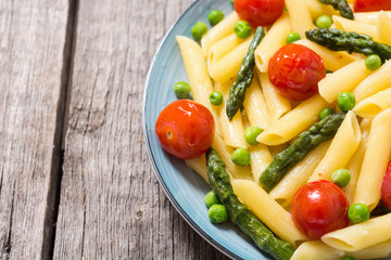 Penne pasta salad with asparagus , tomatoes and peas