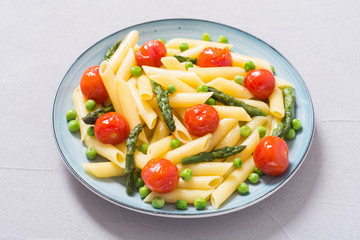 Penne pasta salad with asparagus , tomatoes and peas
