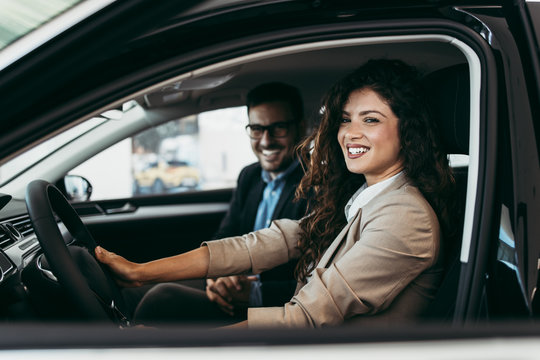 Happy middle age couple enjoying while choosing and buying new car at showroom.