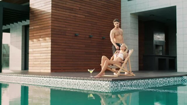 Handsome man touching woman near swimming pool at luxury house.