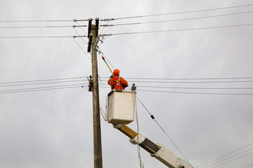 A linesman is lifted up to work on the power lines in rural New Zealand