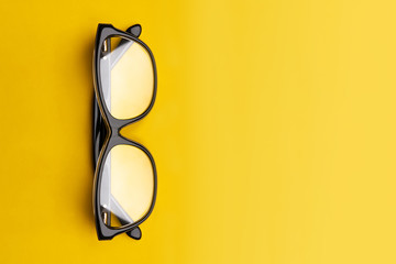 Glasses with transparent lenses isolated on yellow background. Front view with copy space