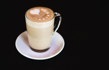 Cup of latte on black background. Photo made in dark key.