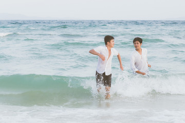 Homosexual portrait young asian couple running with cheerful together on beach in summer, asia gay going tourism for leisure and relax with happiness in vacation at sea, LGBT legal concept.