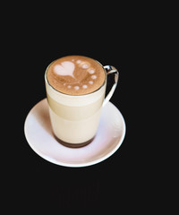 Cup of latte on black background. Photo made in dark key.