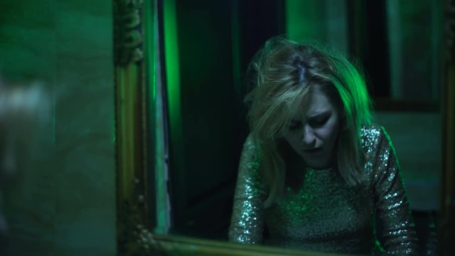 Drunk woman looking in mirror, vomiting after night club party, intoxication