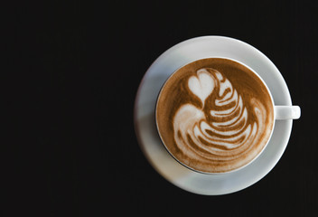 Cup of latte on black background. Photo made in dark key.