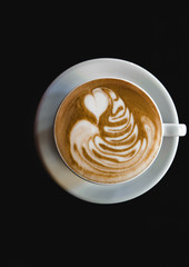 Cup of latte on black background. Photo made in dark key.