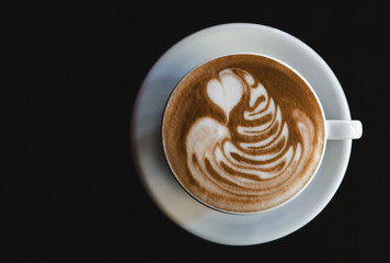 Cup of latte on black background. Photo made in dark key.
