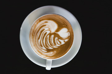 Cup of latte on black background. Photo made in dark key.