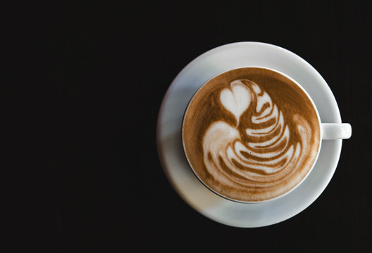 Cup of latte on black background. Photo made in dark key.