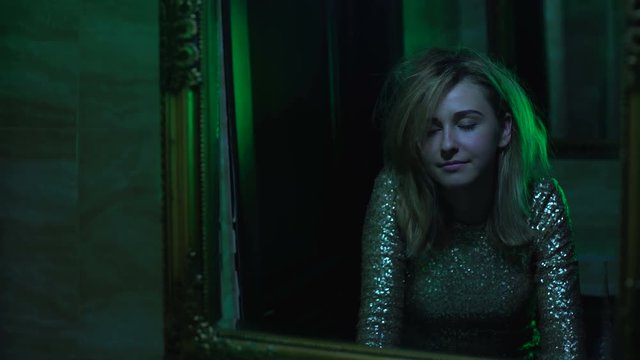 Woman looking in mirror, euphoria after snorting cocaine in night club toilet