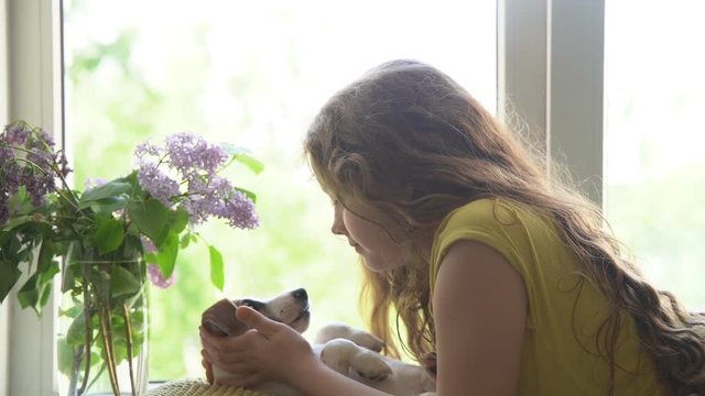 little gir and her puppy resting on the window