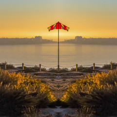 Imgae of a reflected flag on the shore of San Diego with sunset on a clear day
