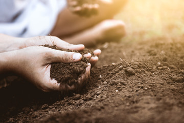 Child and parent holding soil and preparing soil for plant the tree together