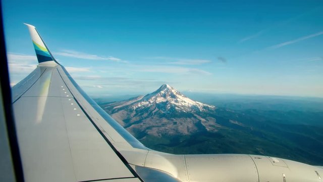 A wide angle shot of Mt. Hood outside of Portland Oregon from a commercial flight featuring the wing of the plane in the foreground.