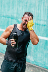 Break time. Exhausted sportsman drinking water after having an intensive workout