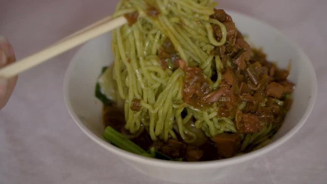 Indonesian street food, mie ayam is chicken noodles with gravy with chicken topping cooked in soy sauce