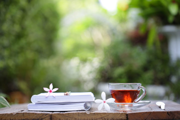 Glass red tea and diary notebook with flower on wooden table