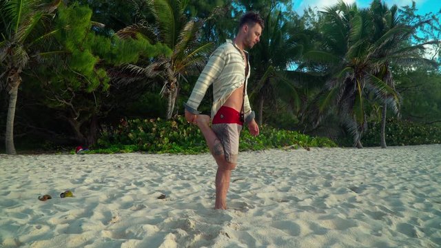 Young man stretching his hamstring on a beach.