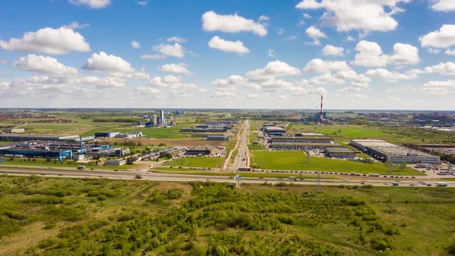 4k aerial hyperlapse of Industrial zone with blue cloudy sky and green fields