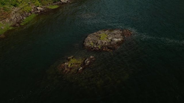Moving, aerial footage of a rocky patch in the river, shot along highway 16 in between Terrace and Prince Rupert around the Skeena River in north-west B.C. Canada during the summer months.