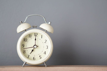 Alarm clock on wooden table with grey background, selective