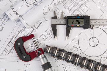 Engineer work. Measurement of the metal part with a caliper on the background of engineering...