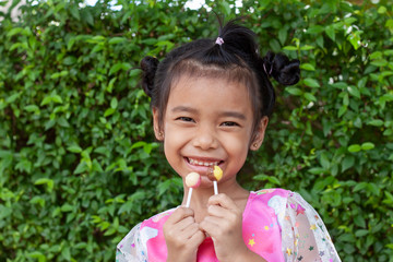 Two hands of girl holding lollipops happily on holiday at the park.