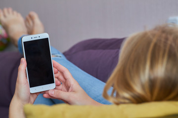 girl lying on the couch with a smartphone in hand