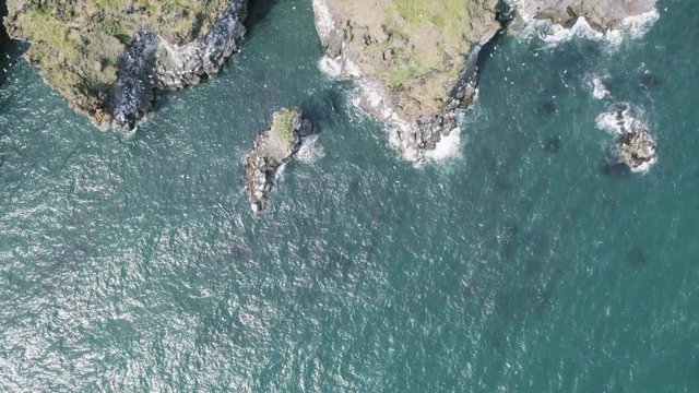 Majestic 4K bird's-eye view aerial of the turquoise North Atlantic ocean and seagulls flying next to the cliffs of Hellnar and Arnarstapi, both popular tourist attraction on the west coast of Iceland.