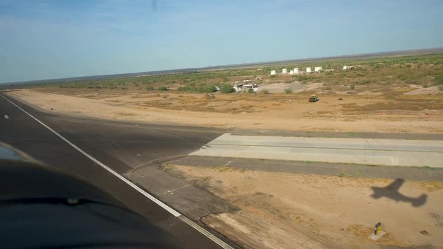 View from the cockpit of a small airplane of the plane's shadow during take off.