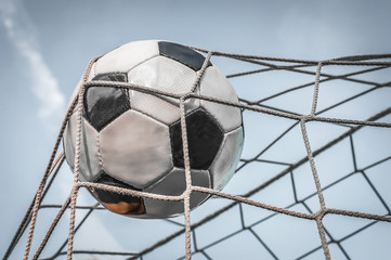 Soccer ball in the goal net with blue sky background