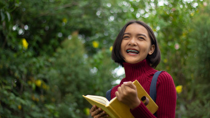 Happy young Asain girl hold notebook with green background.
