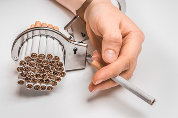 Female hand with handcuffs and cigarettes on white