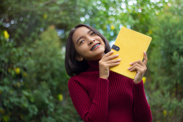 Happy young Asain girl hold notebook with green background.