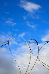 barbed wire on a background of bright blue sky in the shape of a heart