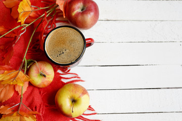 autumn flatlay background with cup of coffee, yellow leaves and and red apples on white wooden table, copy space