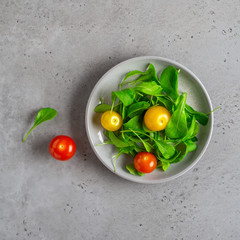 Healthy vegetable salad of fresh arugula and colorful tomatoes. Health care, detox, fitness, diet concept.