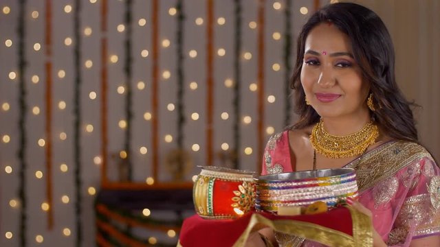 Young beautiful woman smiling and posing at the camera for Karwa Chauth - Indian festival. Indian married lady giving a wide smile on the occasion of Karwa Chauth festival - well dressed in traditi...