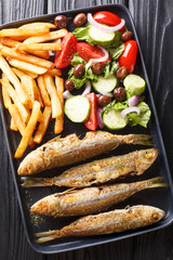 Fried Mediterranean Boops boops fish served with fresh salad and french fries close-up on a plate. Vertical top view