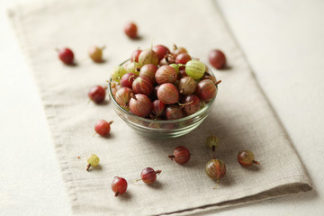 Red and green gooseberries, ripe berries on table in plate.